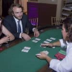Friendly casino dealer teaching guests how to play blackjack at a casino themed party in Surprise, AZ